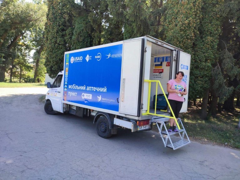 A woman holds her newly acquired medication in front of the mobile pharmacy point